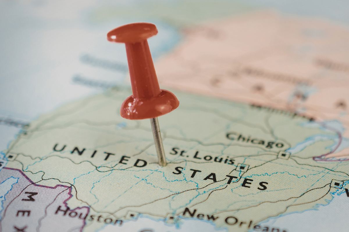 A red pushpin inserted into a map marking the United States, specifically near the text "St. Louis." The map features cities and state outlines.
