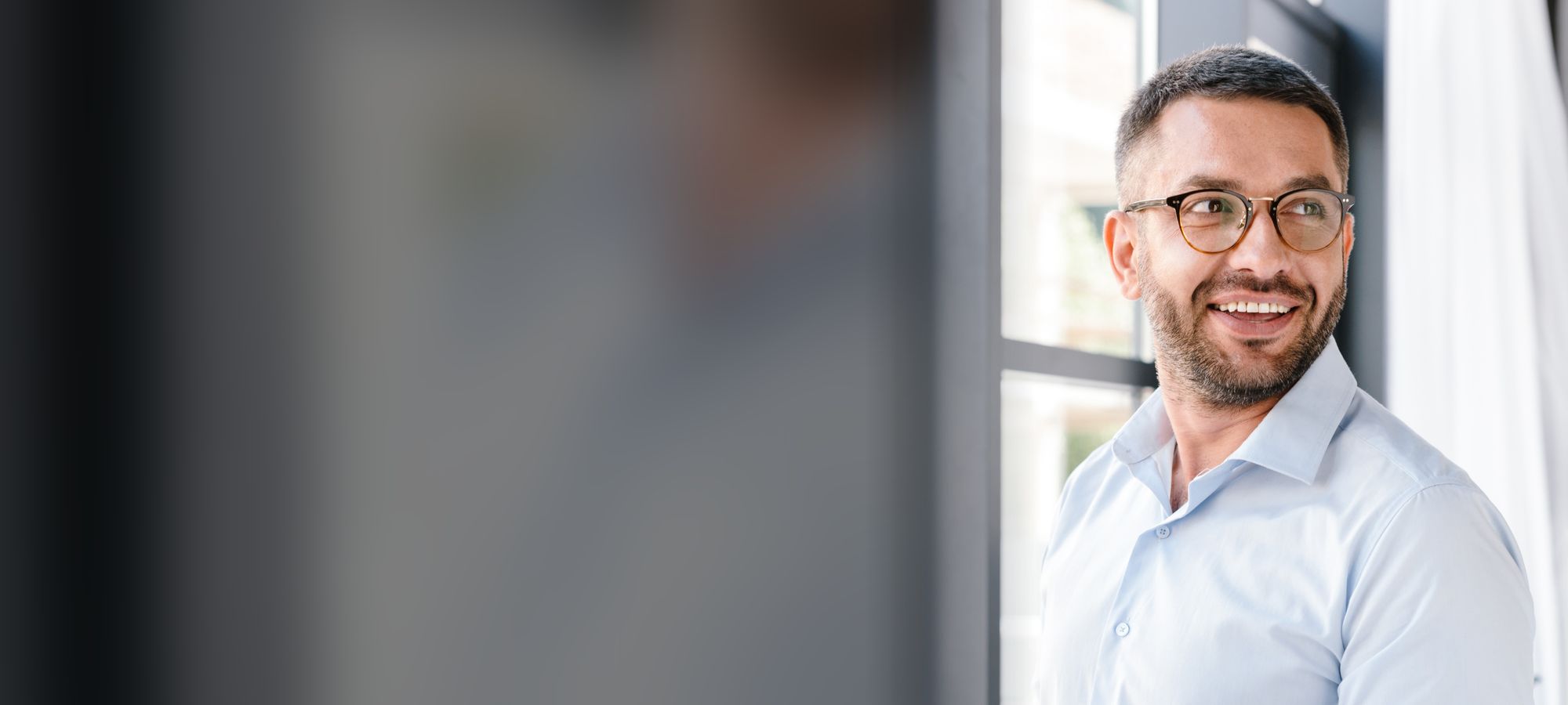 Smiling professional holding a laptop in a bright office
